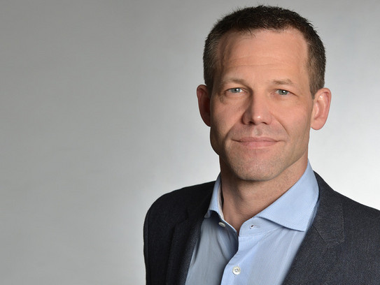 Helml Junger dynamischer Physiker, der freundlich in die Kamera schaut.